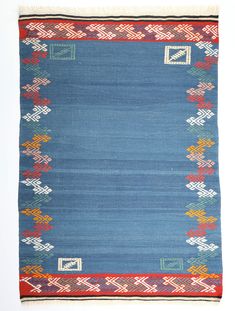 a blue rug with red, yellow and green designs on it's edges is shown