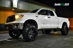 a white truck parked in a parking lot at night