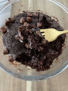 a glass bowl filled with brownie and chocolate chips on top of a wooden table