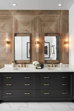 a bathroom with two sinks, mirrors and lights on the wall above them is shown