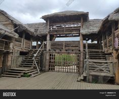 an old wooden building with stairs and thatched roof tops on a cloudy day in the countryside