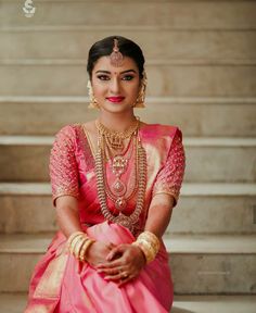 a woman in a pink and gold outfit sitting on some steps