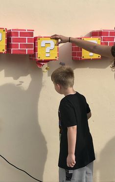 two children are standing in front of a red brick wall with question signs on it