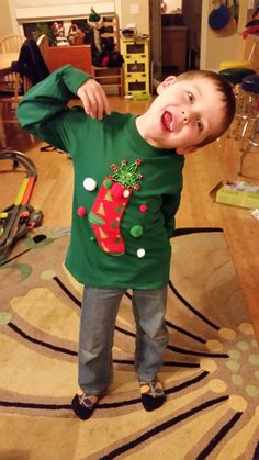 a young boy standing on top of a wooden floor next to a christmas stocking