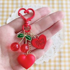 a red heart shaped keychain with cherries hanging from it's sides