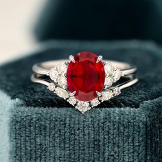 a close up of a ring with a red stone in the middle and white diamonds around it