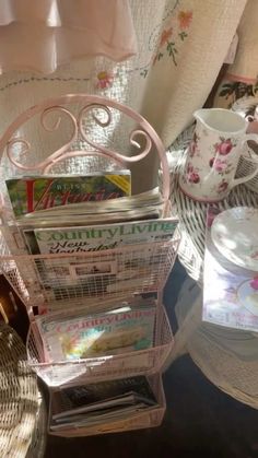 a stack of magazines sitting on top of a table next to a cup and saucer