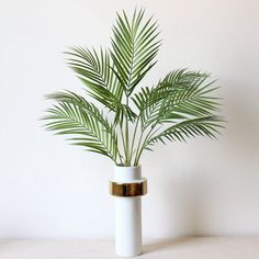 a white vase with a green plant in it