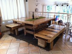 a wooden table and bench made out of pallet wood in a room with tile flooring