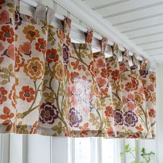 an orange and purple flowered curtain hanging from the side of a window sill