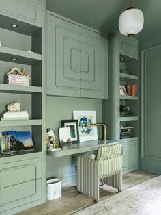 a room with green painted walls and built - in shelvings, including a striped chair