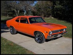 an orange car is parked on the sidewalk