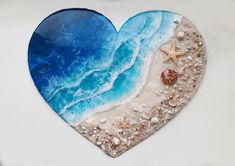 a heart shaped glass plate with shells and starfish on the beach