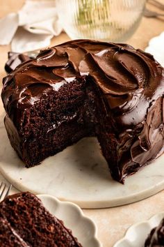 a chocolate cake on a plate with one slice cut out and the rest half eaten