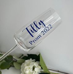 there is a glass with the word tilly on it next to some white flowers