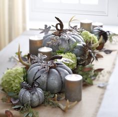 a table topped with candles and silver pumpkins