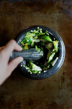 a person is holding a spoon in a bowl filled with broccoli florets