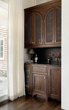 a kitchen with wooden cabinets and white curtains