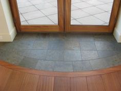 an empty room with wooden doors and tile flooring in front of the glass door