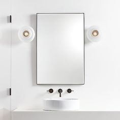 a white bathroom sink sitting under a mirror next to a wall mounted faucet