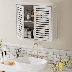 a white sink sitting under a bathroom mirror next to a wooden cabinet with shutters