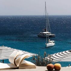 an open book sitting on top of a table next to some boats in the ocean