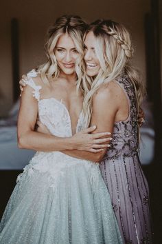 two women hugging each other in front of a bed