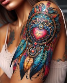 a woman's arm with colorful tattoos and feathers on her shoulder, which has a heart shaped dream catcher in the center