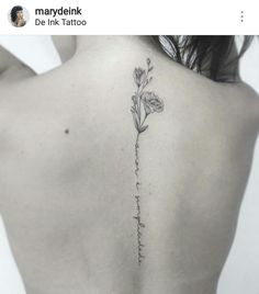 the back of a woman's shoulder with a flower tattoo on her left side