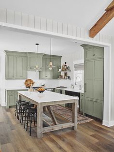 a kitchen with green cabinets and an island in the middle, surrounded by bar stools