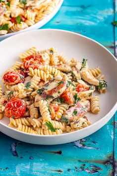 two white plates filled with pasta and tomatoes