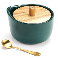 a green bowl with a wooden lid next to a golden spoon