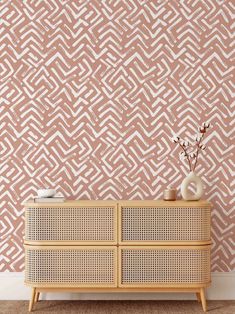 a white vase sitting on top of a wooden dresser next to a pink and white wall