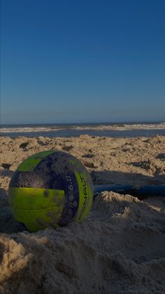 a green and blue beach ball sitting in the sand