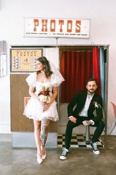 a man sitting next to a woman in a white dress and black suit on the floor