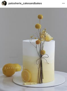 a white cake decorated with yellow flowers and lemons