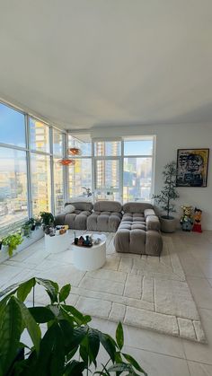 a living room filled with lots of furniture and large windows overlooking the cityscape