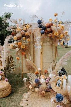 an arrangement of flowers, feathers and pictures on display in the grass at a wedding