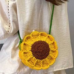 a woman wearing a white shirt holding a yellow and brown crocheted flower purse