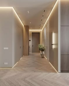 an empty hallway with wooden floors and lighting on the walls is lit by recessed lights