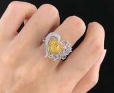 a woman's hand holding a yellow and white diamond ring