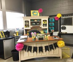 an office decorated with yellow and pink flowers, tissue pom poms, black and white decor