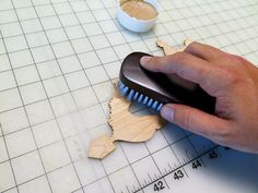 a person is using a brush to cut out the shape of a piece of wood