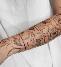 a woman's arm covered in tattoos with flowers and leaves on the arm sleeve