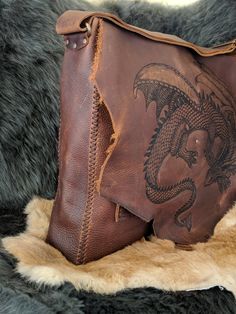 The Slumbering Dragon Messenger Bag We will make you a custom, unique bag just for you. Handmade, hand stitched, one of a kind leather messenger bag. It is made from extremely durable stone oil leather that offers beautiful color variation and texture as well as water resistance and lifelong use. The bag measures roughly 15 in by 13 in with a 3 in gusset. The front has three additional pockets one is 11.5 in by 8.5 in and the other two are 5 in by 6 in. The strap is completely adjustable and the Hand-stitched Leather Tote Satchel, Hand-stitched Leather Satchel Shoulder Bag, Hand-stitched Leather Shoulder Bag, Hand Tooled Leather Satchel Shoulder Bag, Artisan Leather Crossbody Satchel, Artisan Hand Tooled Leather Saddle Bag, Artisan Hand-tooled Leather Saddle Bag, Hand-stitched Leather Satchel, Handmade Leather Artisan Satchel