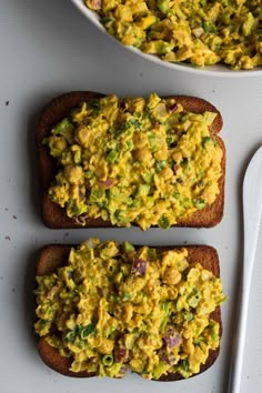 two pieces of bread with scrambled eggs on them next to a bowl of broccoli