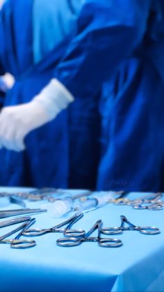 two surgeons in blue scrubs and white gloves are preparing to perform surgery on an operating table