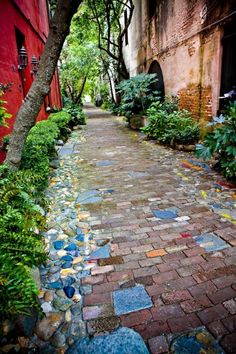 a cobblestone path in an alley between two buildings with trees on either side