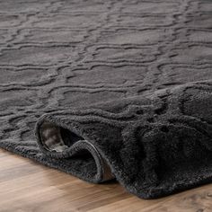 an area rug on the floor that has been made with dark colored wool and is very soft