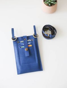 a blue bag sitting on top of a white table next to a potted plant